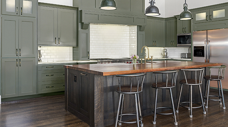 Kitchen with deep green cabinetry, butcher-block island and subway tile