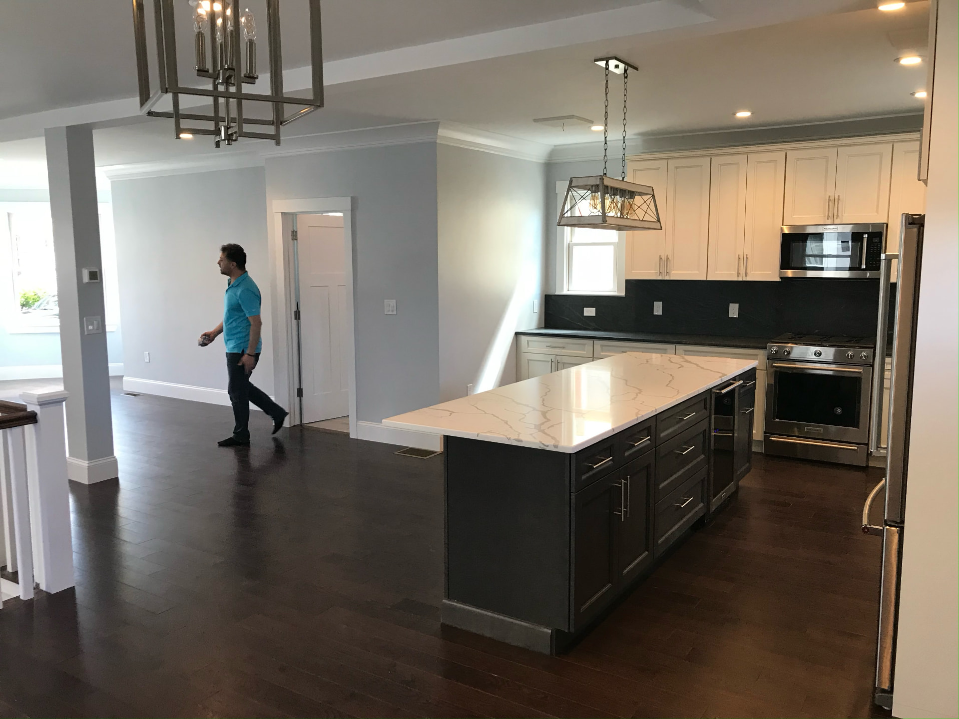 Open kitchen with quartz waterfall island and dark hardwood floors