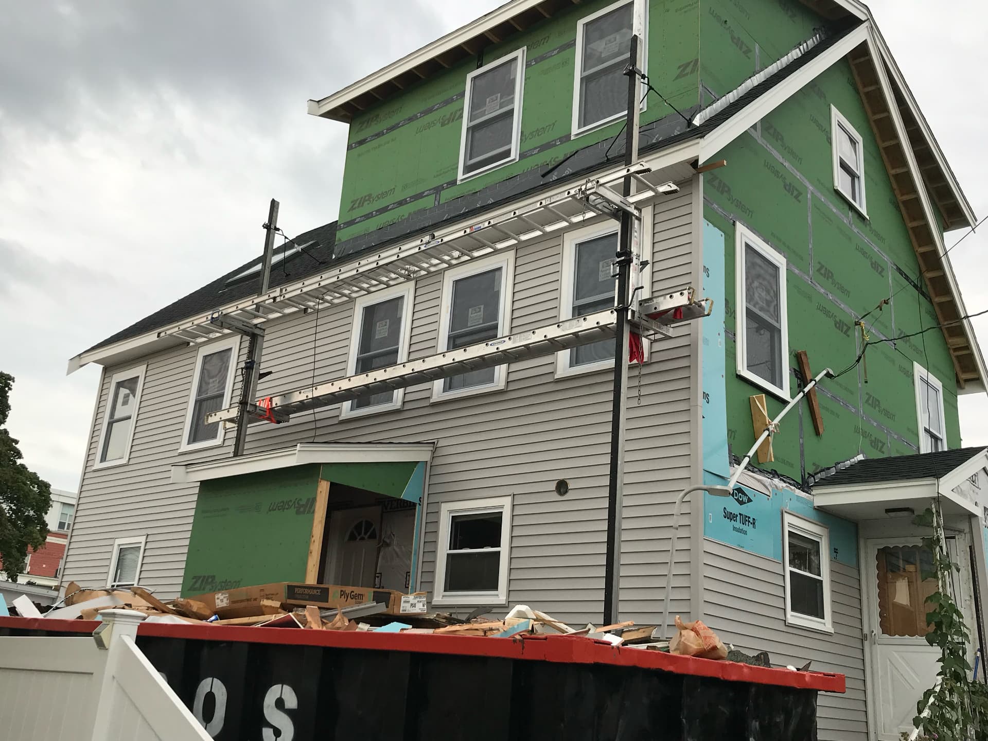 Siding installation in progress across the new addition