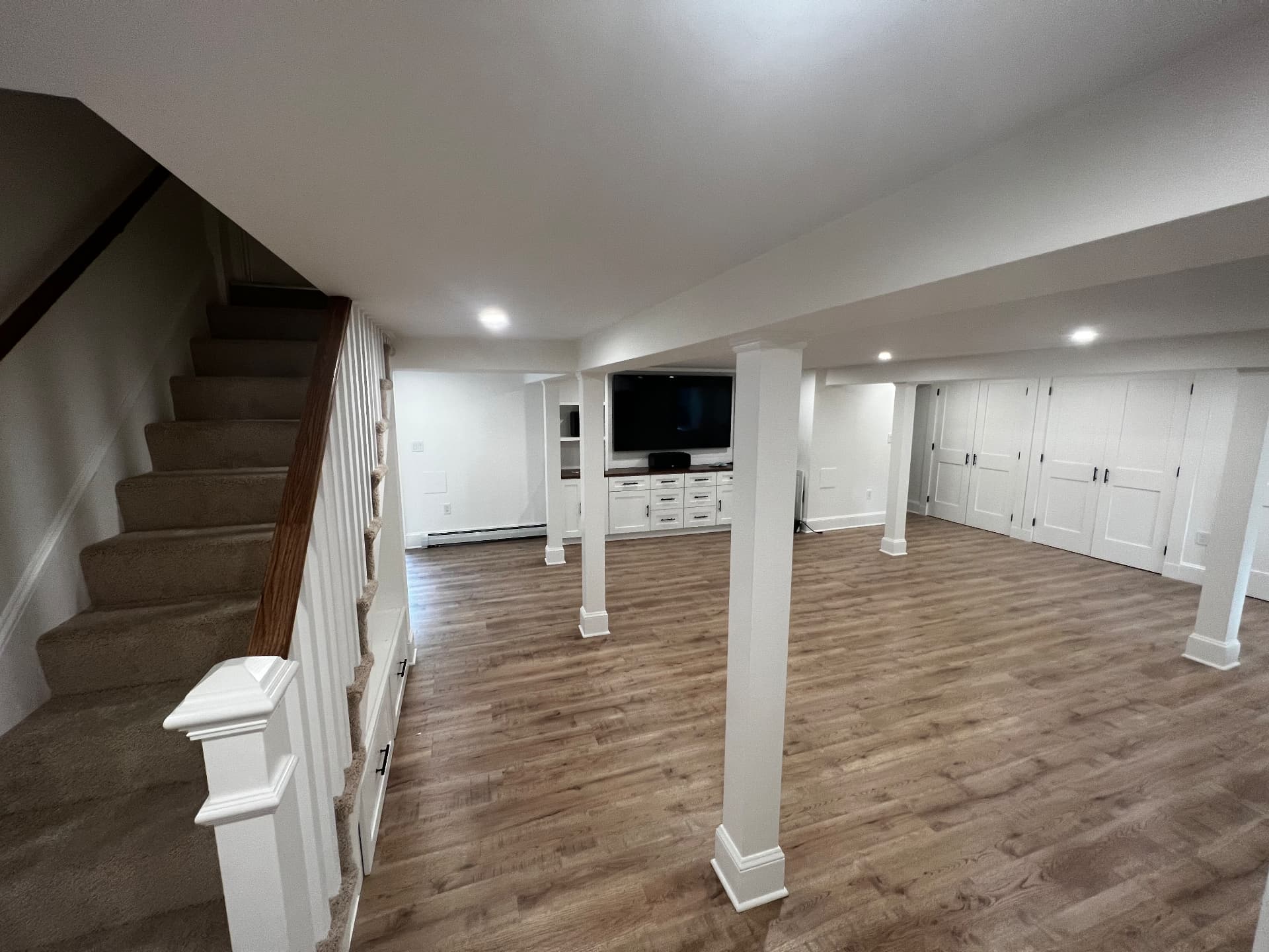 Finished basement family room with built-in media wall and wood-look flooring