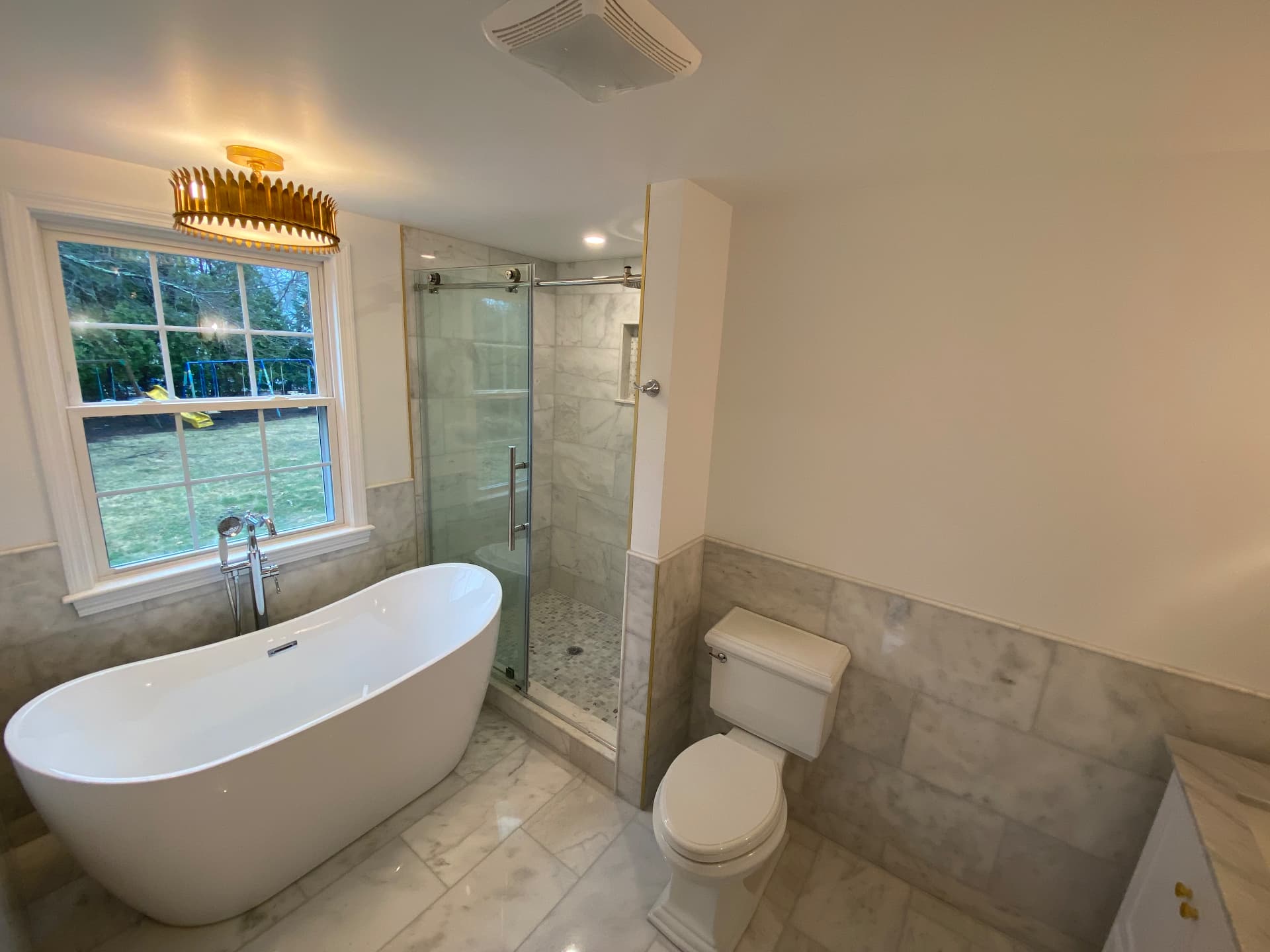 Primary bathroom with freestanding tub, marble tile and glass shower