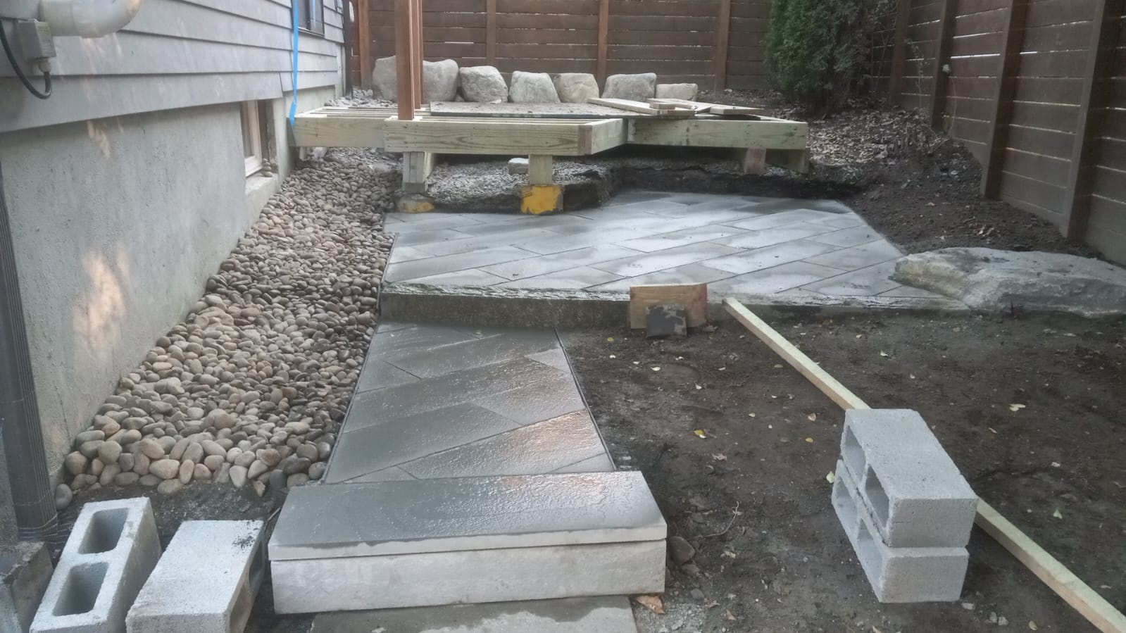 Bluestone patio and walkway laid with river-stone drainage bed along the foundation