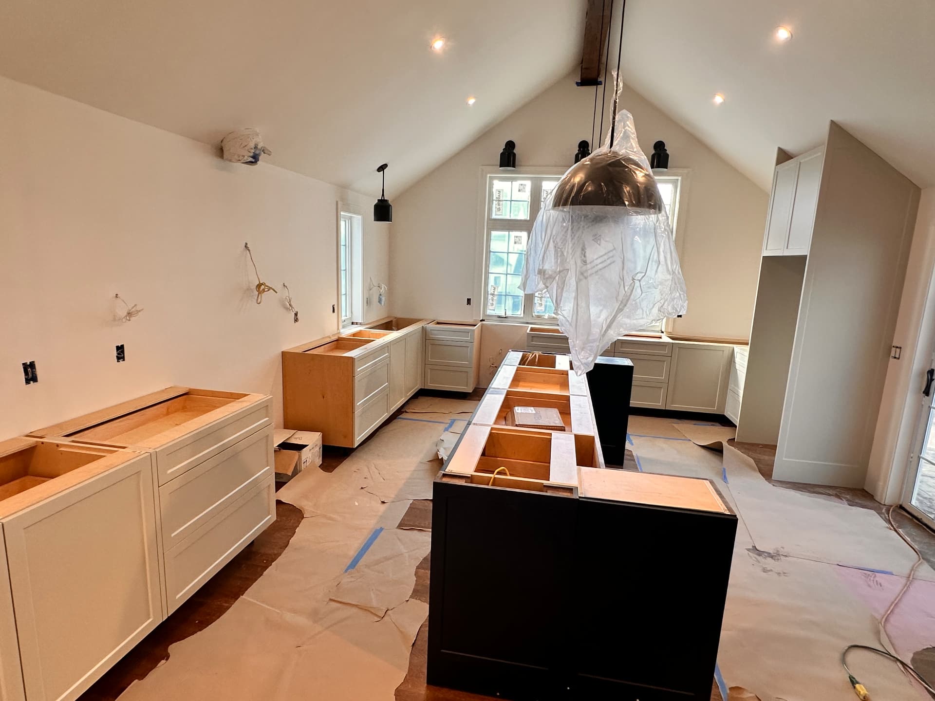 Custom kitchen cabinetry being installed under the vaulted ceiling