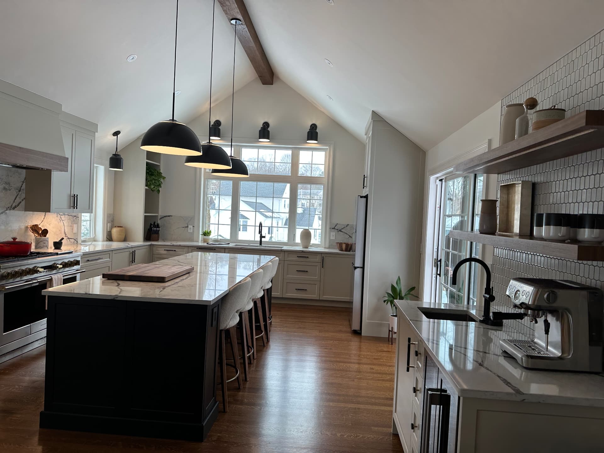 Finished vaulted kitchen with marble island and black pendant lighting