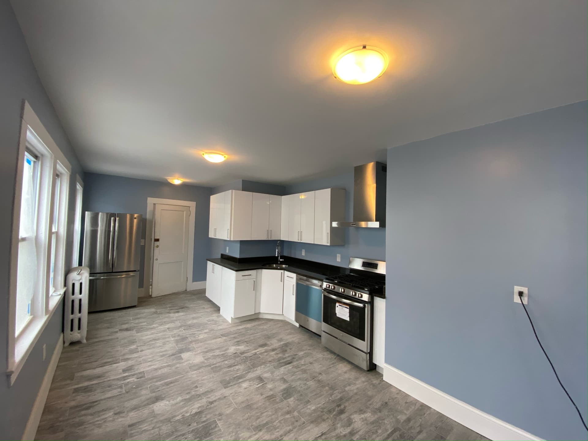 Bright kitchen with white cabinets, stainless appliances and tile flooring