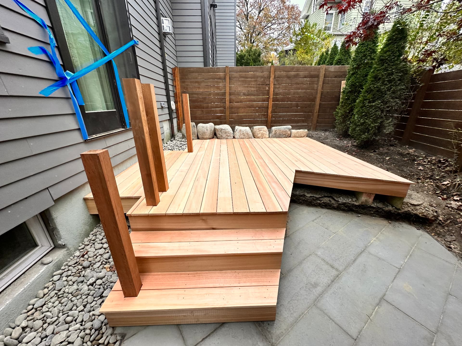 Cedar deck steps and privacy screen posts over the bluestone patio