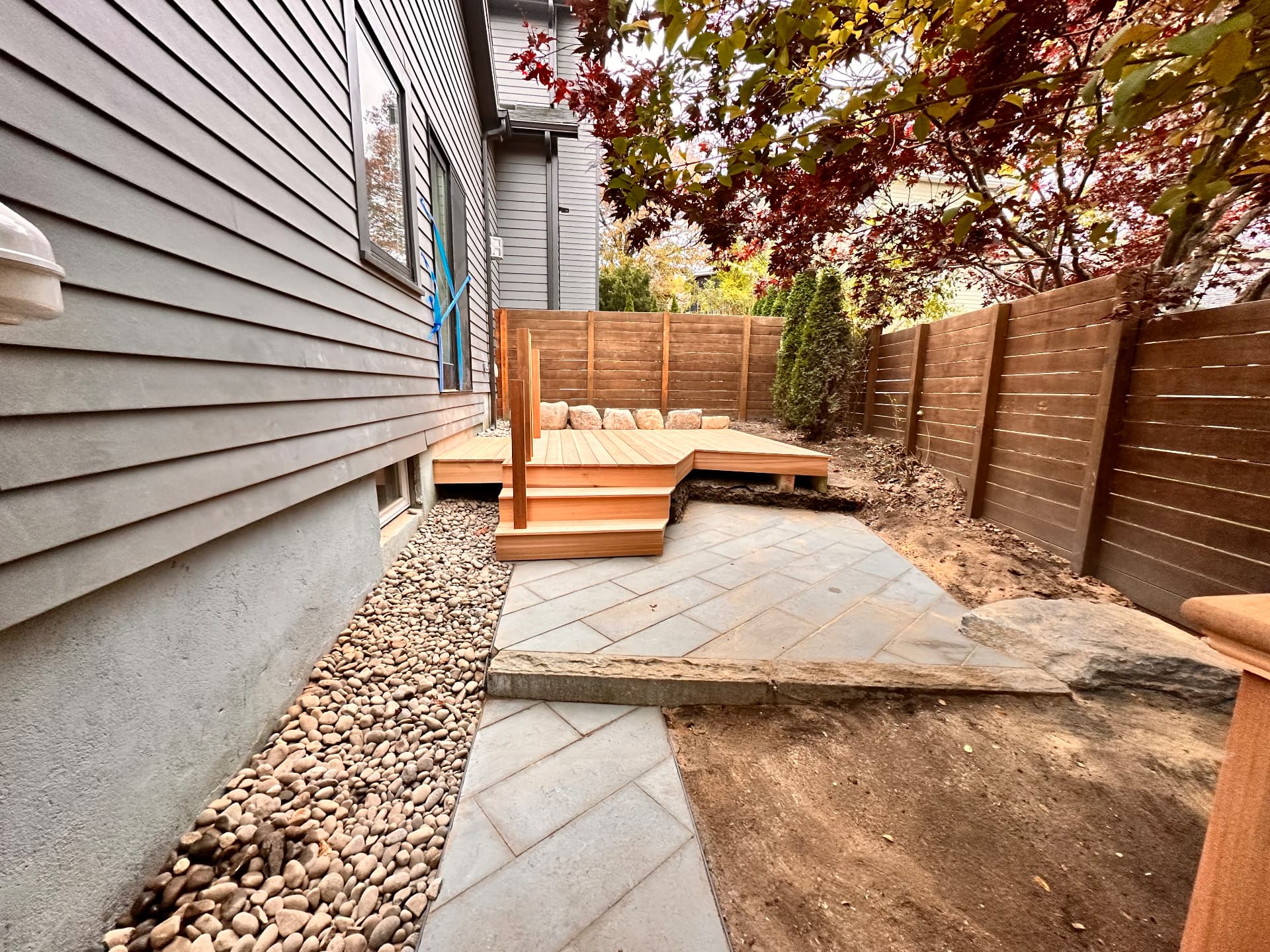 Finished cedar deck and bluestone patio in a landscaped side yard
