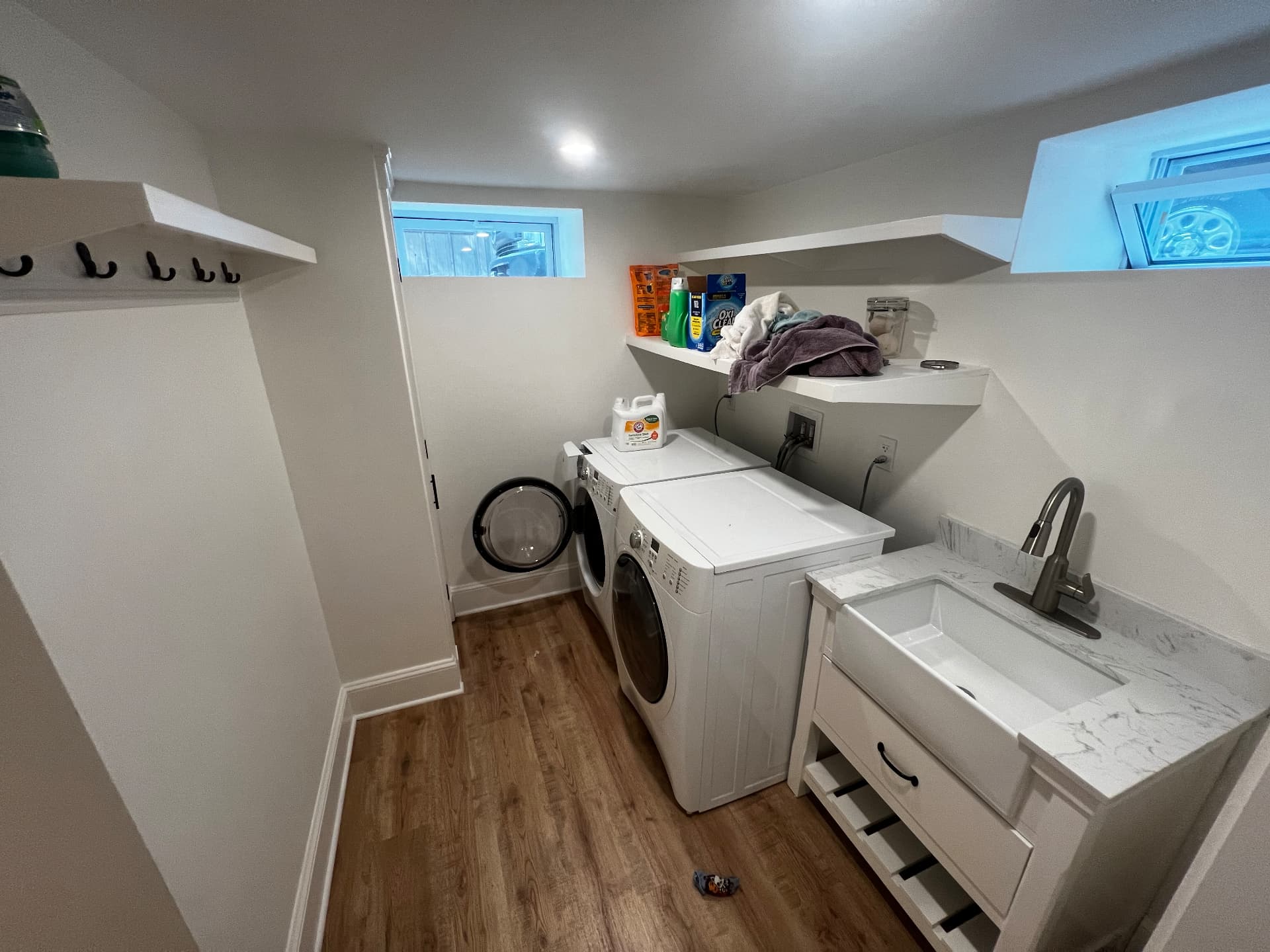 Basement laundry room with utility sink, stone counter and floating shelves
