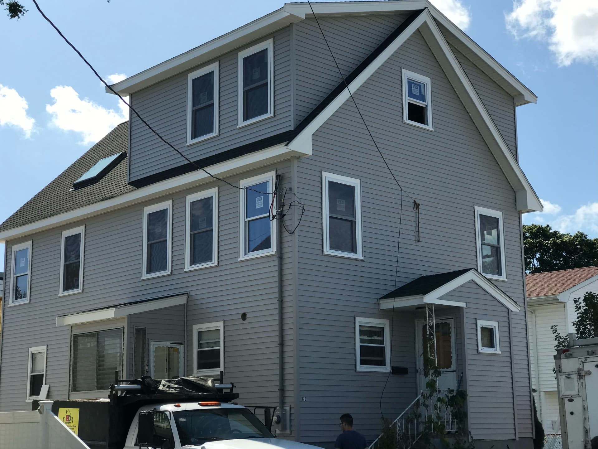 Completed second-story addition with new gray siding and white trim