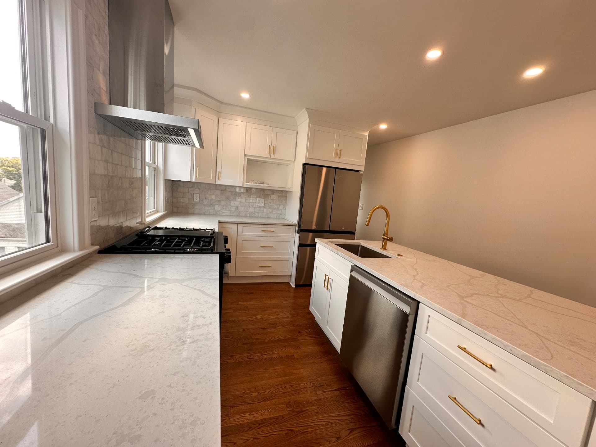 Finished kitchen with marble tile backsplash, brass fixtures and stainless appliances