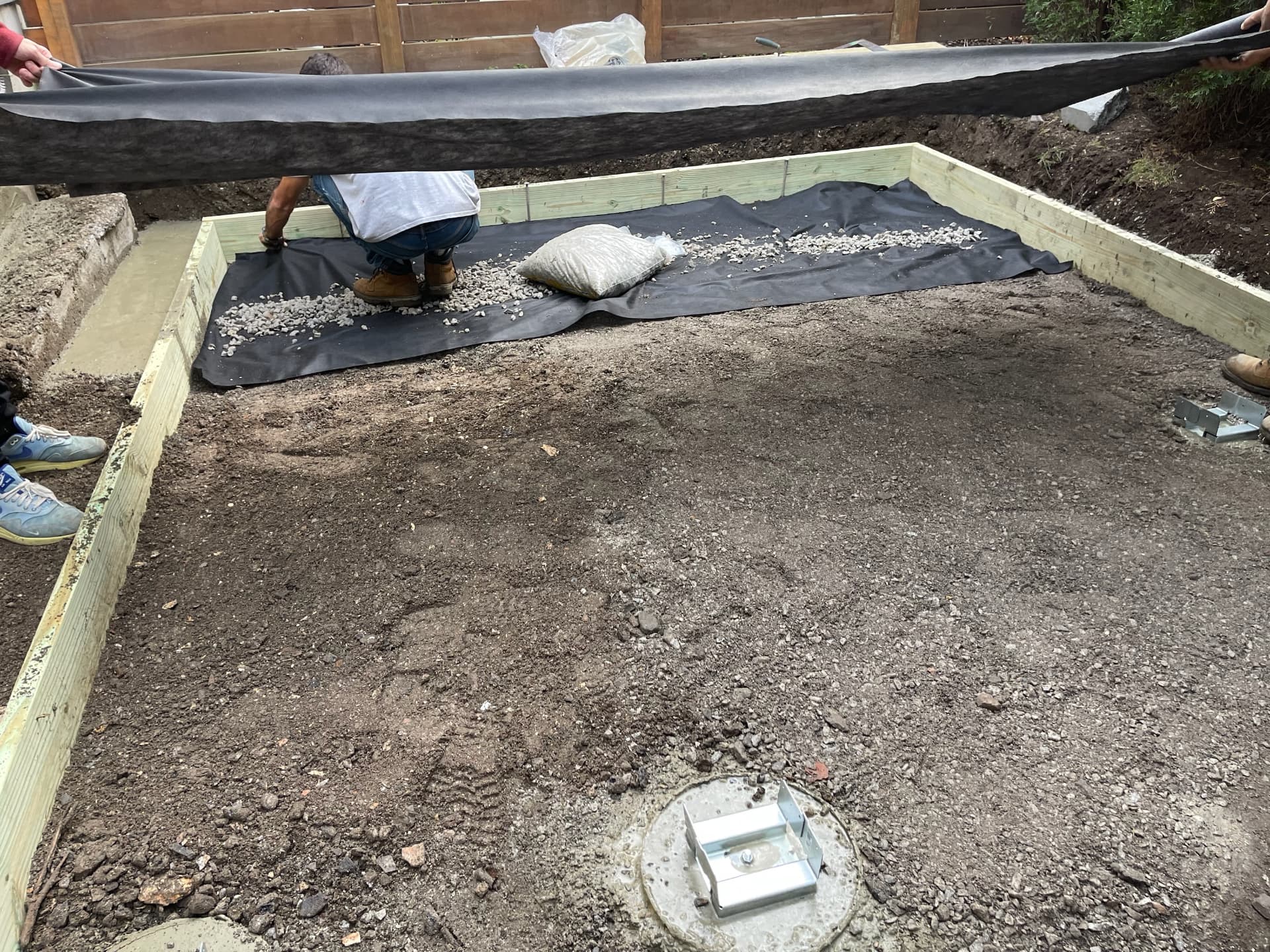Filter fabric and crushed stone base being installed inside timber forms