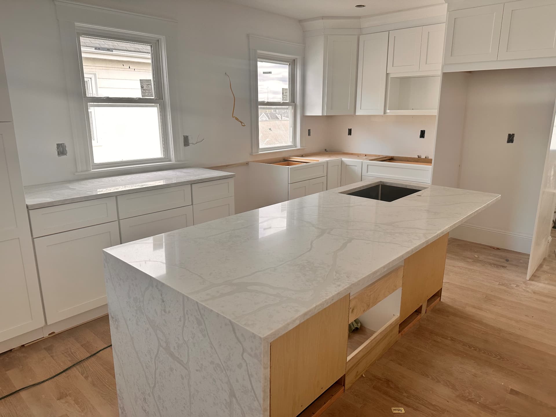Kitchen cabinetry set with quartz waterfall island during installation